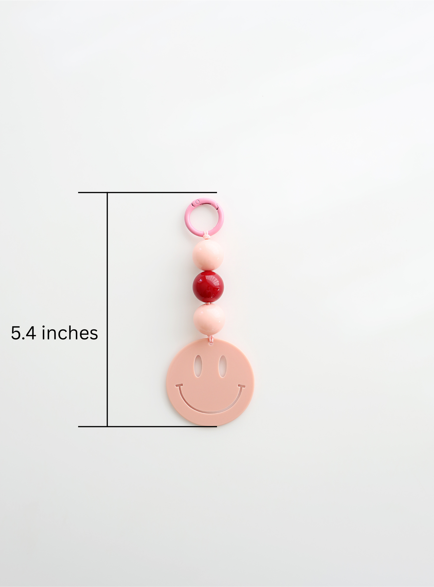 One colorful smiley face keychain, in pink, featuring round pastel beads and a large smiley face charm, showing its measurement of length, 5.4inches on a white background.