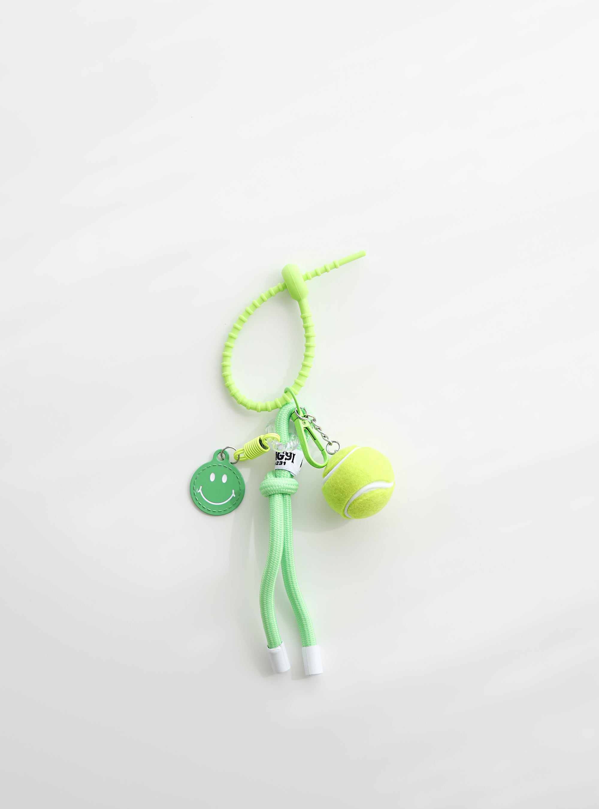A bright green tennis ball keychain featuring a mini tennis ball charm, a green smiley face tag, and an adjustable loop strap for easy attachment, displayed on a clean white background.