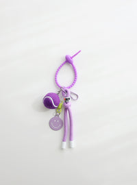 A bright purple tennis ball keychain featuring a mini tennis ball charm, a purple smiley face tag, and an adjustable loop strap for easy attachment, displayed on a clean white background.