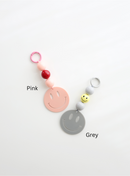 Two colorful smiley face keychains, one in pink and one in grey, each featuring round pastel beads and a large smiley face charm, labeled with their color names on a white background.