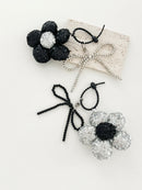 Two sequined flower keychains in black and silver with matching bead bow charms, displayed on a neutral background.