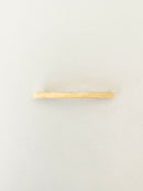 One slim rectangular hair clip in marbled shades of yellow, neatly displayed on a white surface.