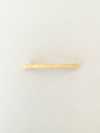 One slim rectangular hair clip in marbled shades of yellow, neatly displayed on a white surface.