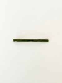 One slim rectangular hair clip in marbled shades of dark green, neatly displayed on a white surface.