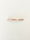 One slim rectangular hair clip in marbled shades of pink neatly displayed on a white surface.