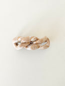 Beige hair clip with a chain-link design on a white background