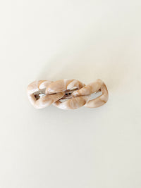 Beige hair clip with a chain-link design on a white background