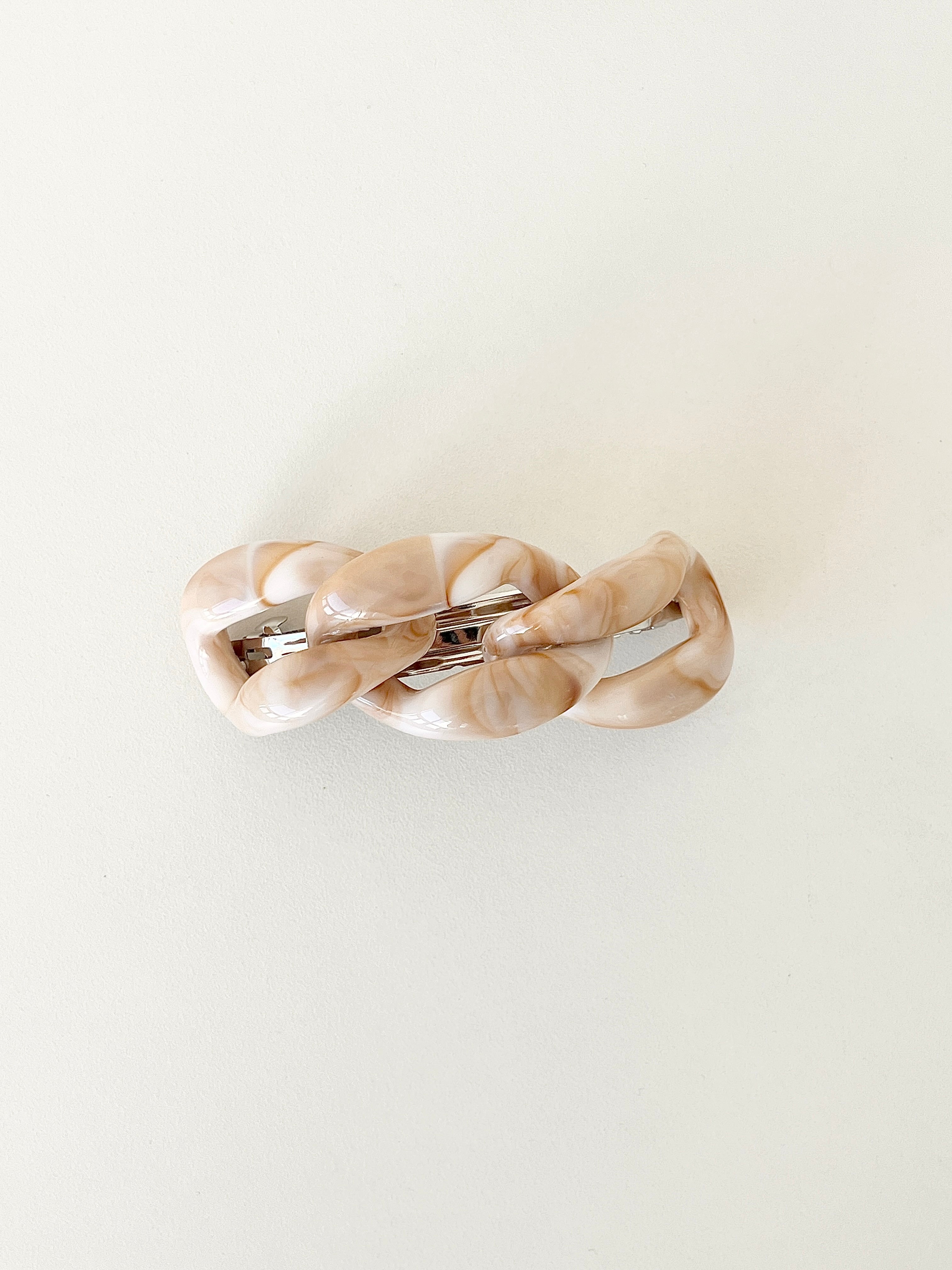 Beige hair clip with a chain-link design on a white background