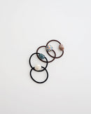 Four elastic hair ties in black and brown, each featuring a glossy mosaic-style bead in ivory, teal, pastel, and mauve tones, displayed on white background.